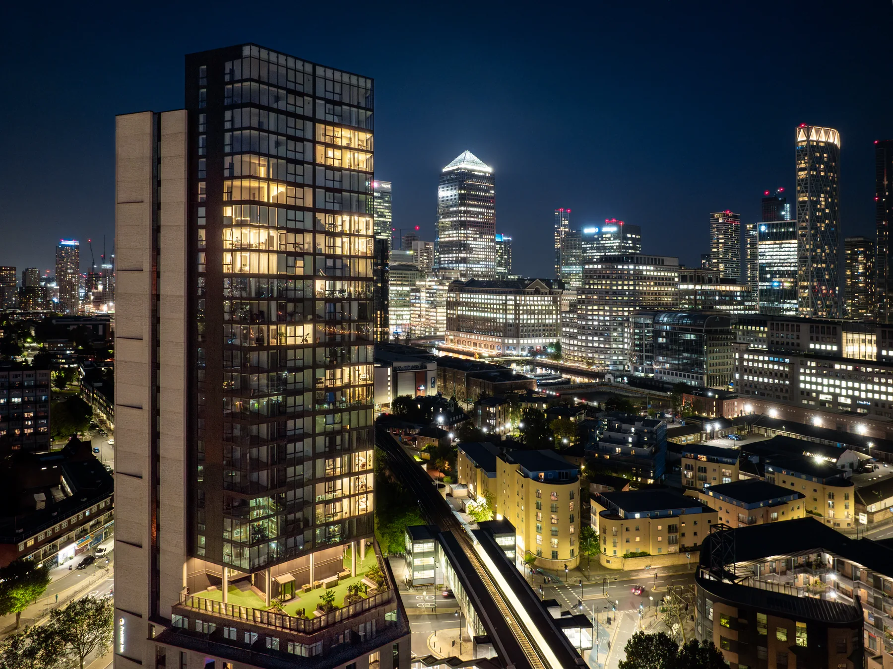 Vetro illuminated at night against the Canary Wharf skyline